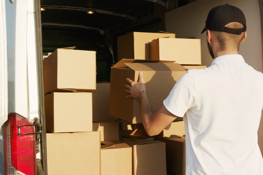 Courier organising cardboard boxes in the back of a van