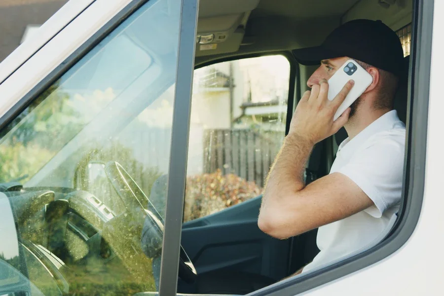 Delivery driver making a phone call from his van window