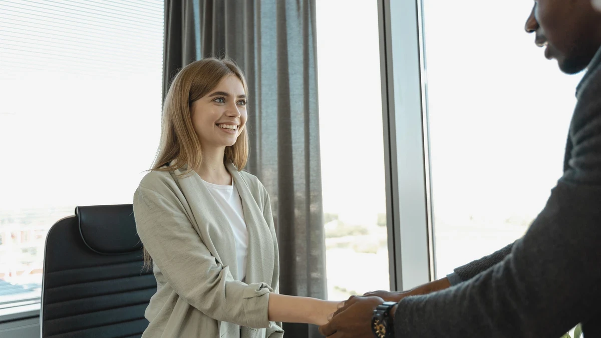 Smiling candidate shaking hands with an interviewer in a bright office