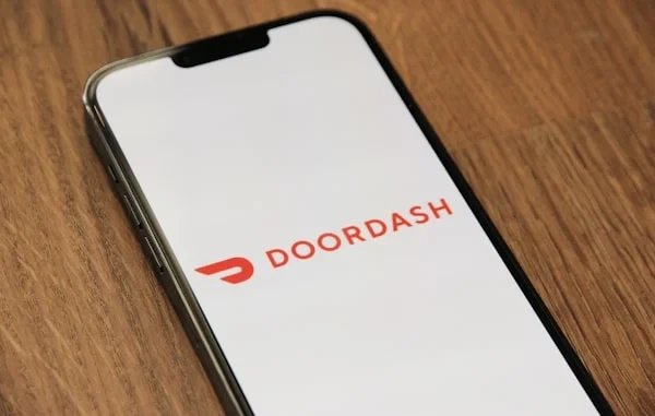 DoorDash logo on a smartphone screen, lying on a wooden table