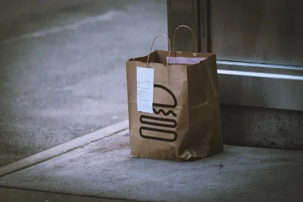 Brown paper takeout bag with a stapled receipt left on a doorstep