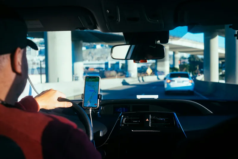 Delivery driver at the wheel following a route on a phone mounted to the dashboard