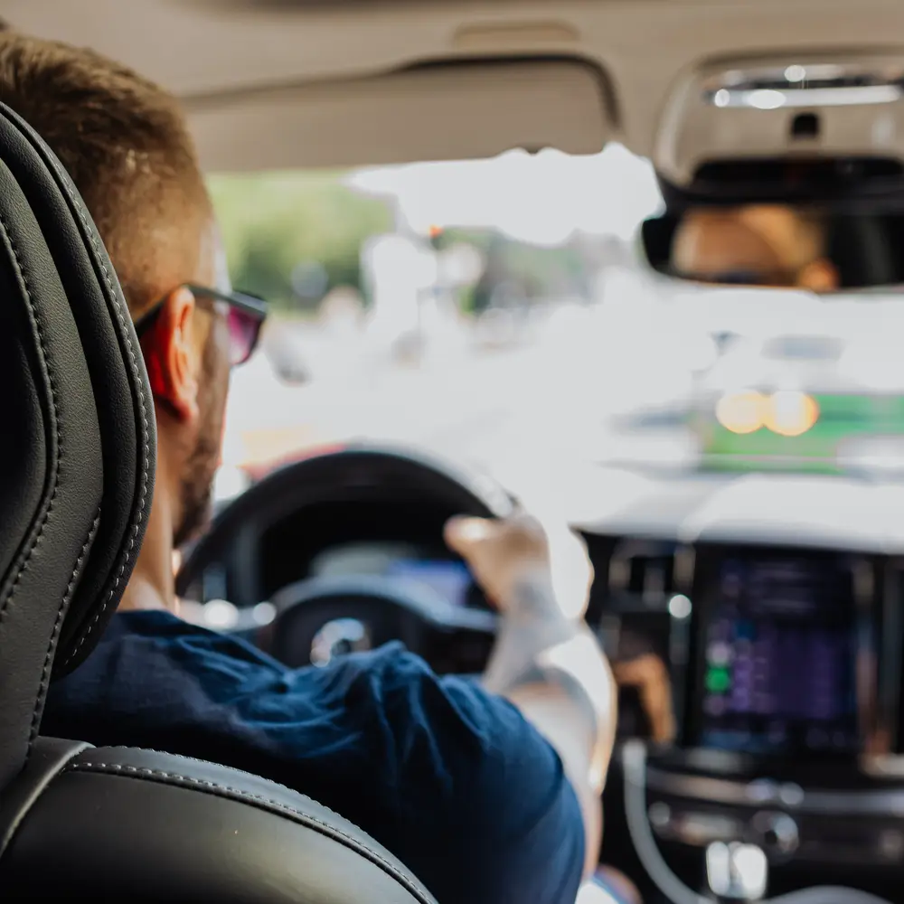 A driver at the wheel of a car, moving through city traffic