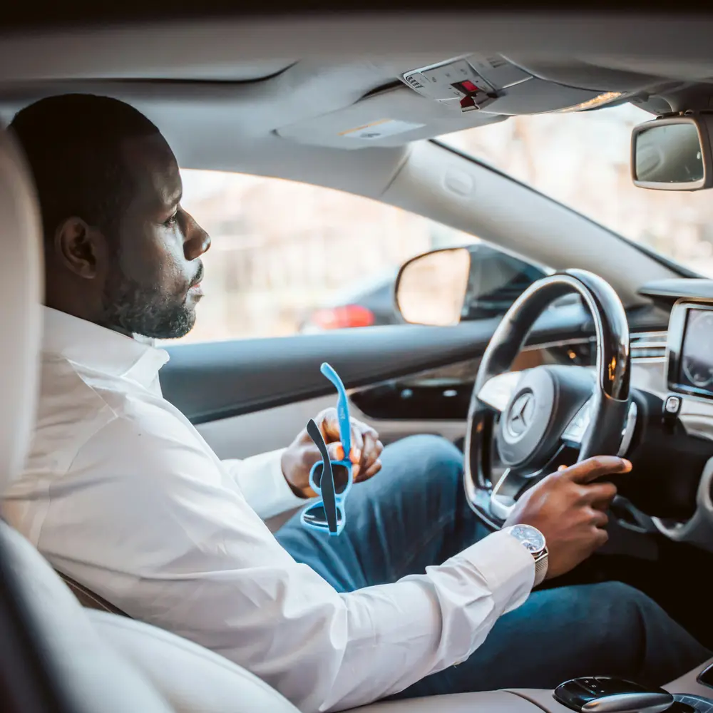 A driver at the wheel of a sedan, waiting before a passenger pickup
