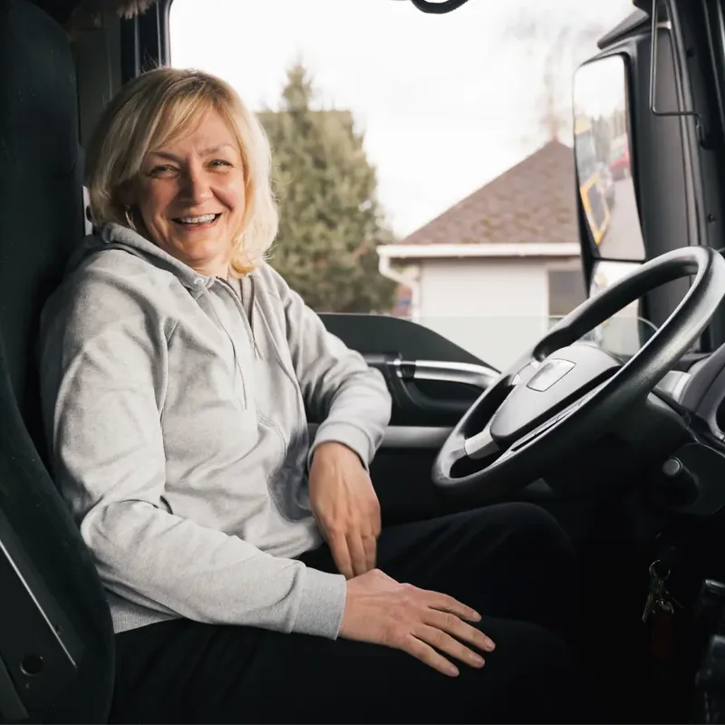 Smiling female truck driver in the cabin of her vehicle during a training session