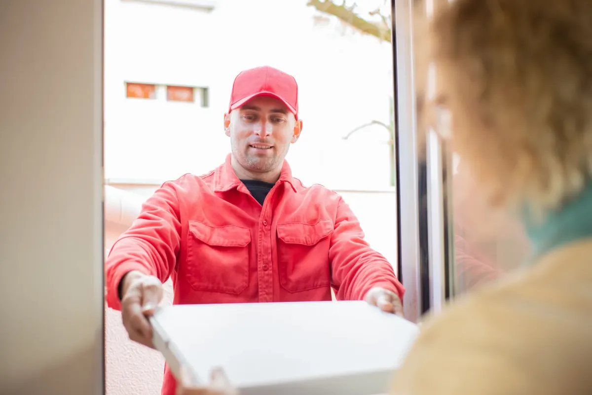 Part time delivery driver handing a food order to a customer at their front door