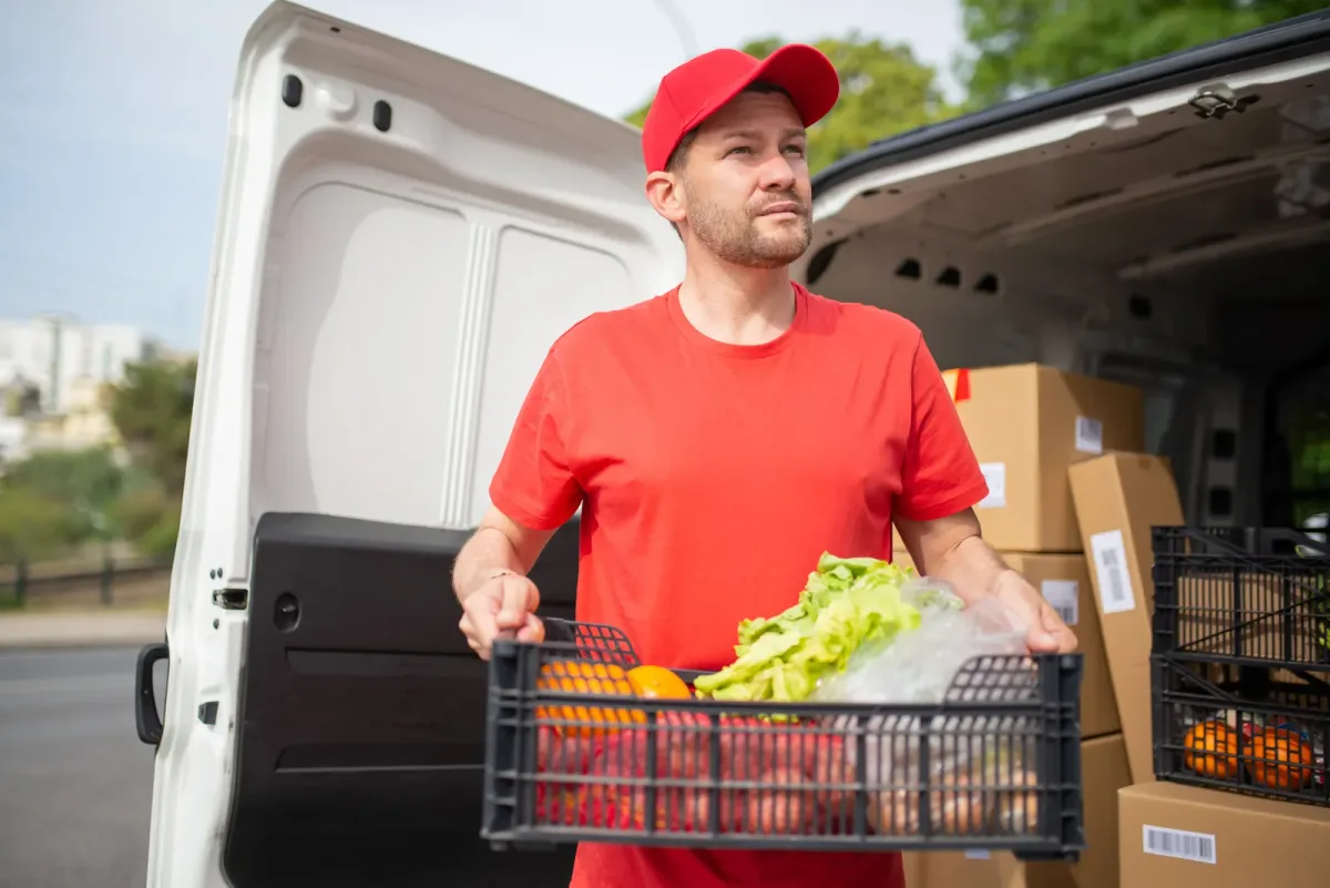 Grocery delivery driver unloading crates from the back of a supermarket delivery van
