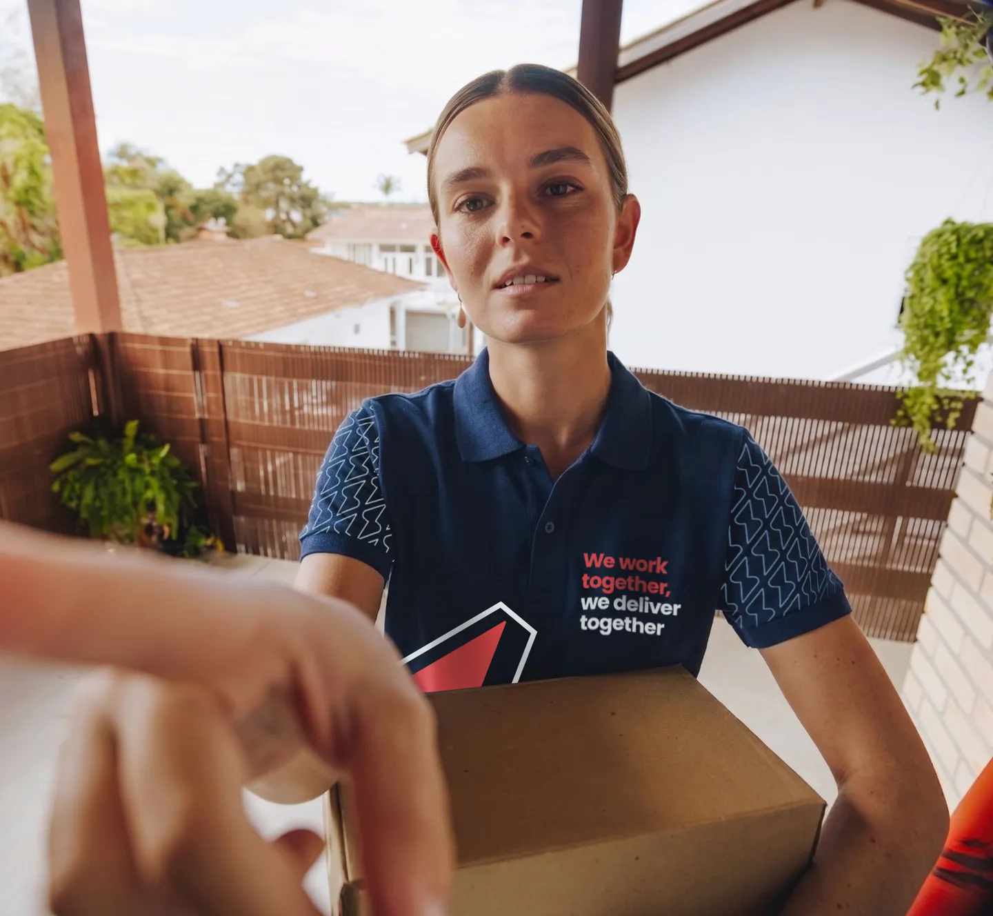 A Service Club courier in branded uniform handing a parcel to a customer at the door