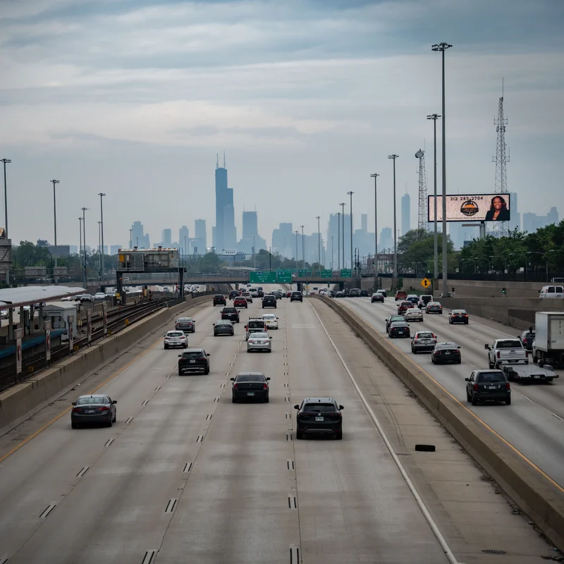 The Kennedy Expressway running towards the downtown Chicago skyline, with a CTA train line alongside