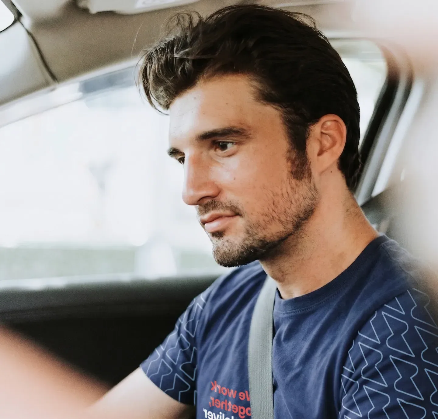 A driver in a Service Club shirt at the wheel of his van