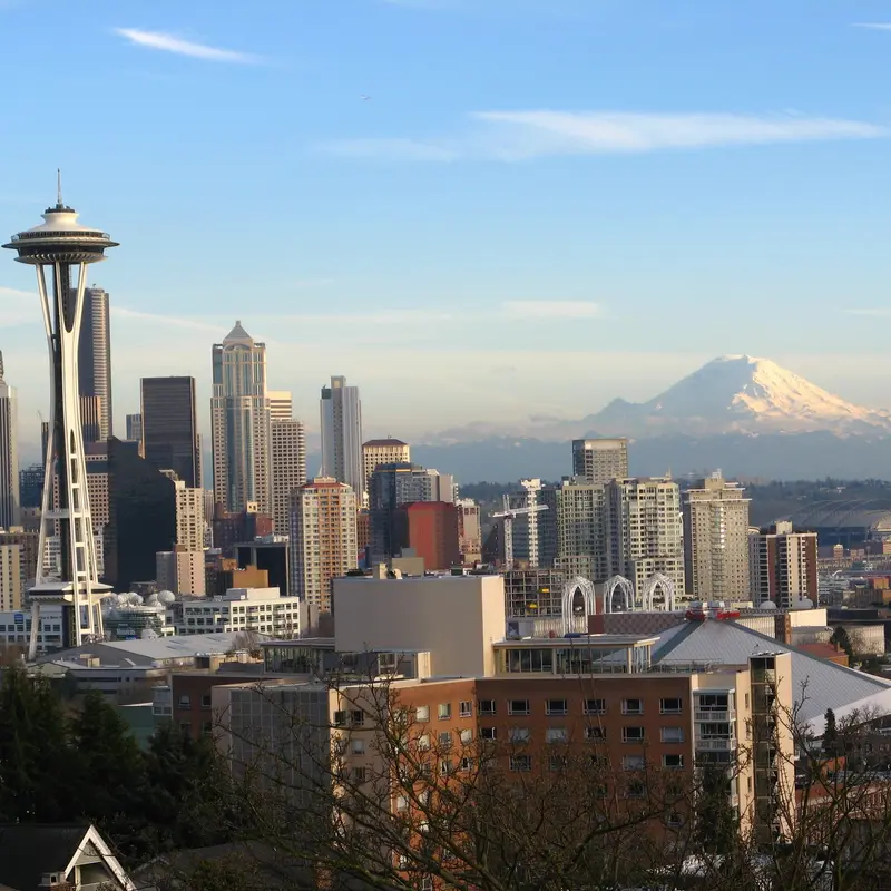 The Space Needle and the downtown Seattle skyline, with Mount Rainier rising behind them under a clear sky