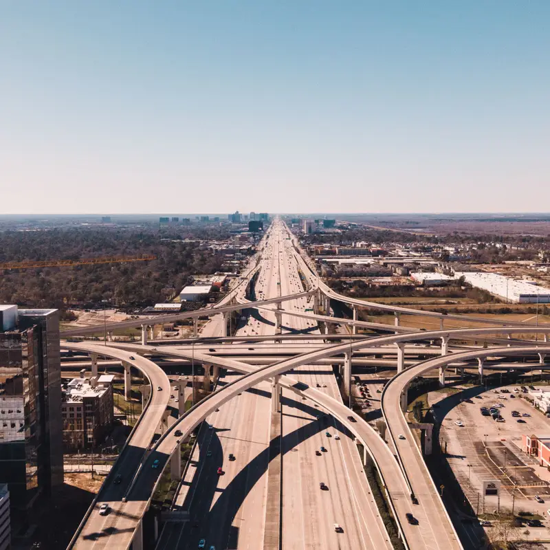 An aerial view of a multi-level freeway interchange in Houston, with the highway running straight out to a flat horizon