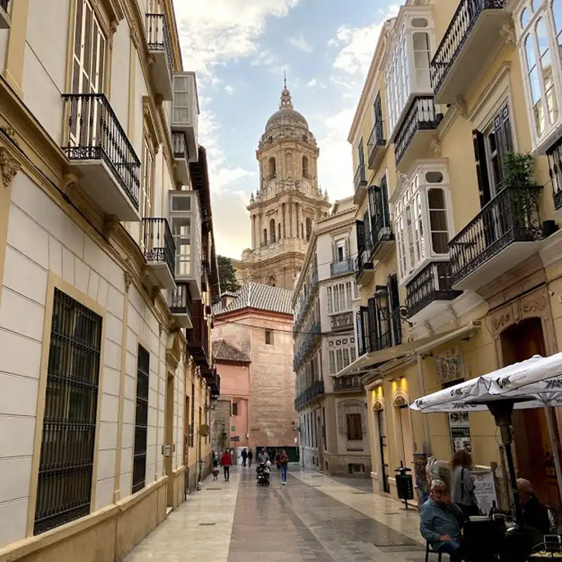 Calle peatonal del centro de Málaga con balcones y terrazas, y la torre de la catedral al fondo