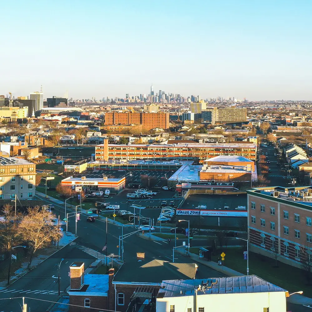 Newark streets and rooftops with the Manhattan skyline on the horizon