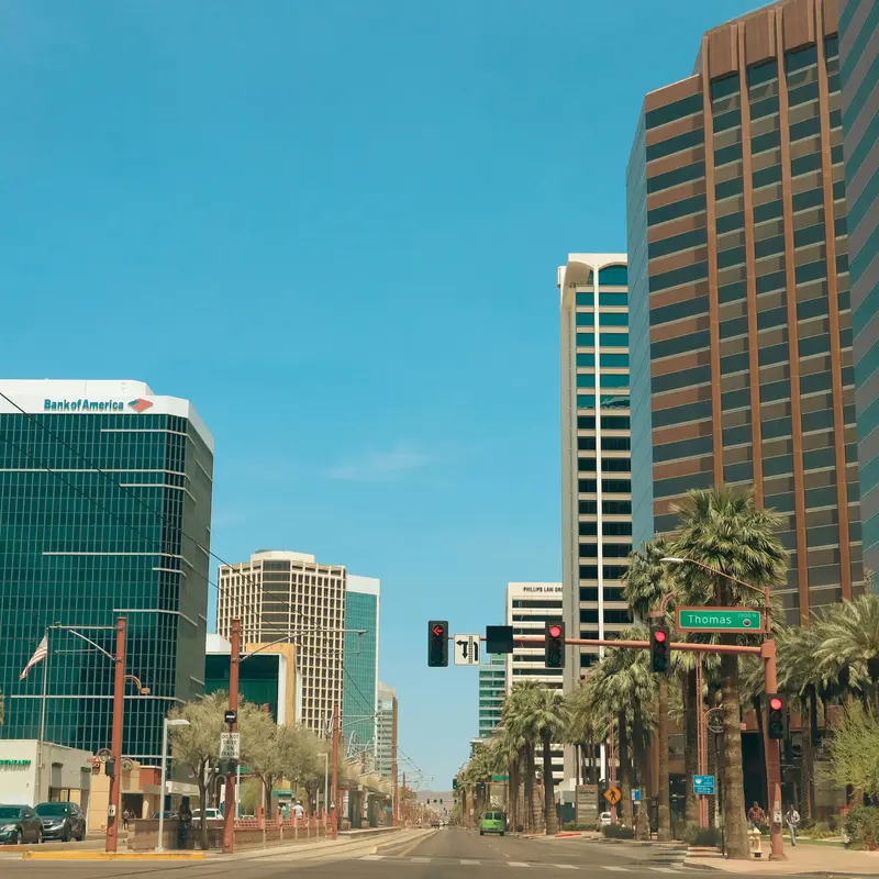 Central Avenue in uptown Phoenix at the Thomas Road traffic light, with palm trees, glass office towers and a clear blue sky