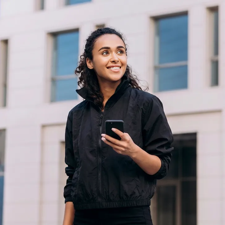 A delivery driver checking her phone outside an office building