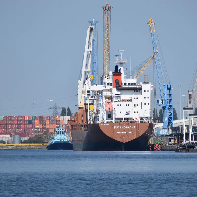 A cargo ship moored at the Southampton docks, with stacked shipping containers and cranes behind it