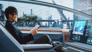 A man sits in the back seat of a self-driving taxi robot. He is wearing a suit and tie, and he is holding a newspaper. The taxi is driving down a city street.