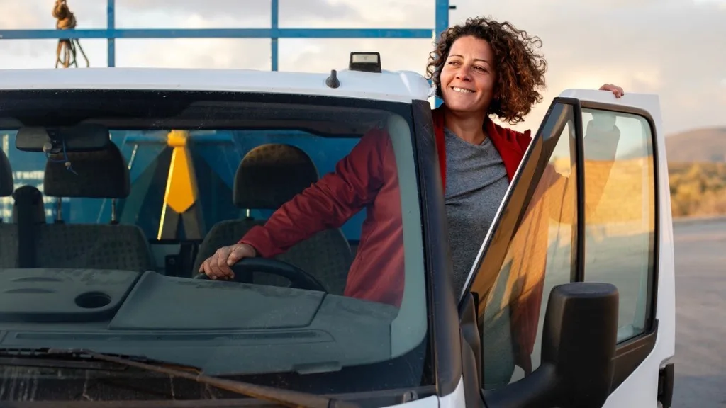 A professional van driver standing outside her truck smiling confidently